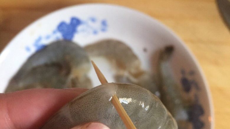 一虾两吃,用牙签戳虾背处取虾线, 再将虾身的虾壳剥净。