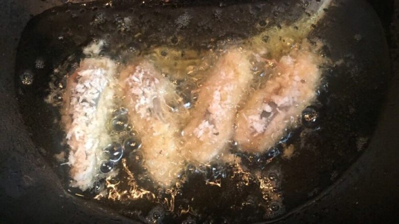 一虾两吃,锅内放油烧热,虾头入锅内炸熟至表面金黄捞出沥干。