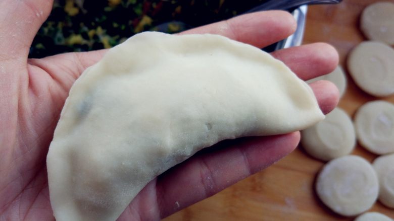 扇贝韭菜盒子,馅中加盐,拌匀,放在擀好的面片中间,对折后捏合边缘