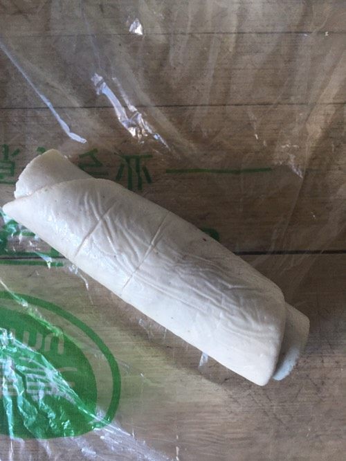少油版伍仁点心,擀好的面团从一头开始卷起来,如图。