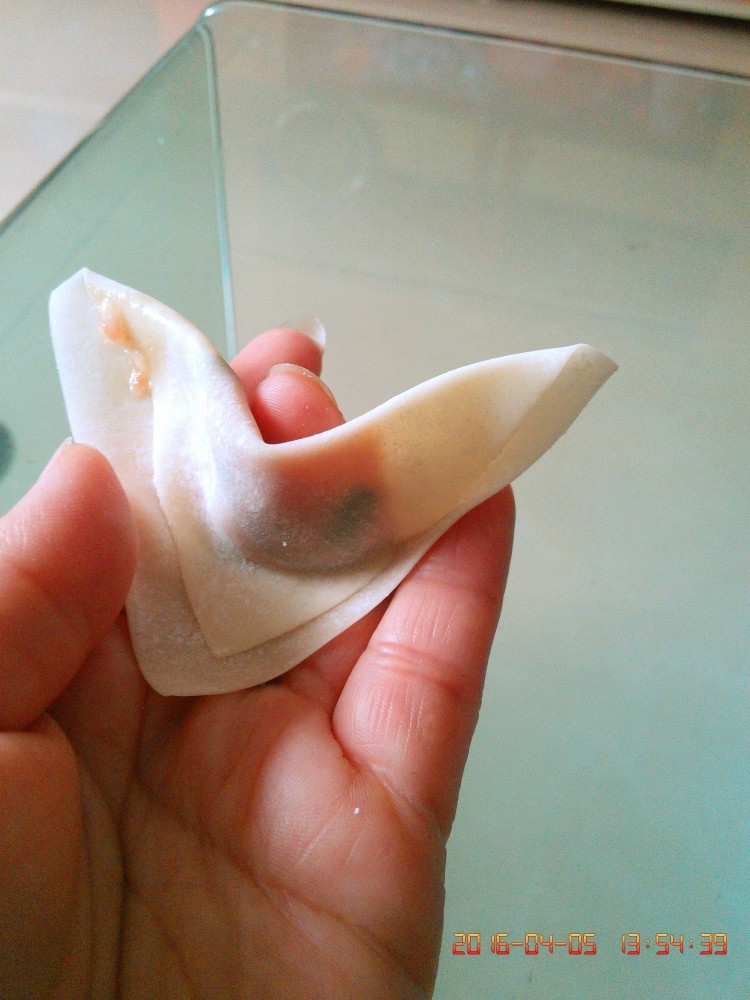 炸抄手,在左上角抹水或肉馅做粘合剂,中指往上抬,把左右两个角粘合在一起即可。