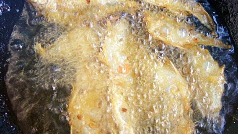 酥脆功夫鱼,开始炸鱼,每次下锅的鱼不要太多,双面煎黄即可夹出,再依次油炸下一批小鱼,炸好捞出盛盘放置。停过。