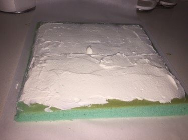 蓝天白云蛋糕卷,再把蛋糕翻过来,就是蛋糕的正面朝上,把奶油铺在上面,靠近身体的部分可铺的厚一些。