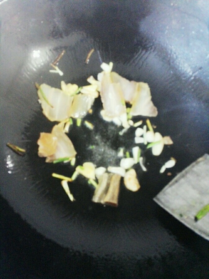 咸肉烧鳝鱼,起油锅放入葱蒜姜洗好的咸肉,翻炒出油。