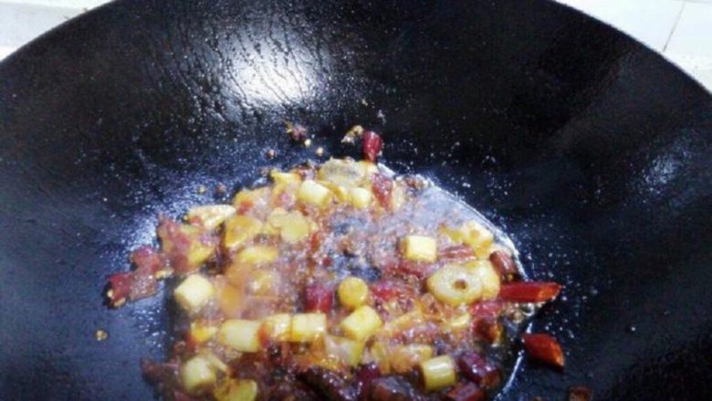红烧香辣鱼块,锅里倒入油,大火烧热放入姜蒜大葱白和豆瓣酱炒香,再放入干辣椒花椒翻炒。