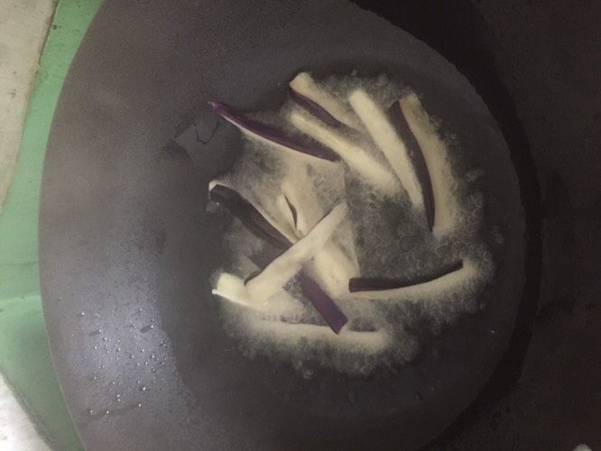 豆瓣茄子,锅里倒入适量油,油烧至7-8成热时,下茄子,快速翻滚 炸至茄子表面有点起焦感 捞出备用