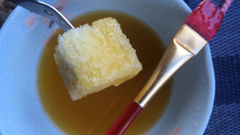 面包诱惑,拿把叉子叉一块吐司丁,用刷子整个都刷一层蜂蜜黄油液