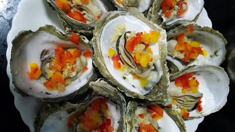 水蒸海蛎子+#人民的美食#,先将蒜蓉,彩椒点缀在每个海蛎子上,量随意