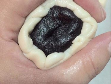 豆沙酥,取一份面团，手指按中间将两头往中间按，用擀面杖擀成面皮，包入准备好的豆沙捏紧收口向下，放到烤盘上。