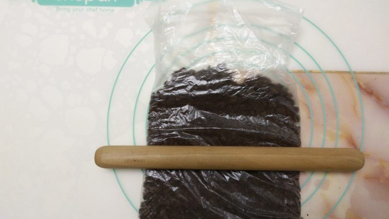 免烤快手高颜值的甜点——火龙果慕斯蛋糕 ,奥利奥饼干碎放入保鲜袋中,用擀面杖擀成粉状。