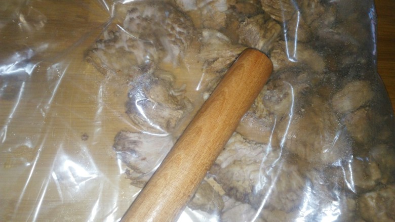 炒锅版猪肉松,将肉装进保鲜袋,用擀面杖一边擀一边敲,将肉敲散。