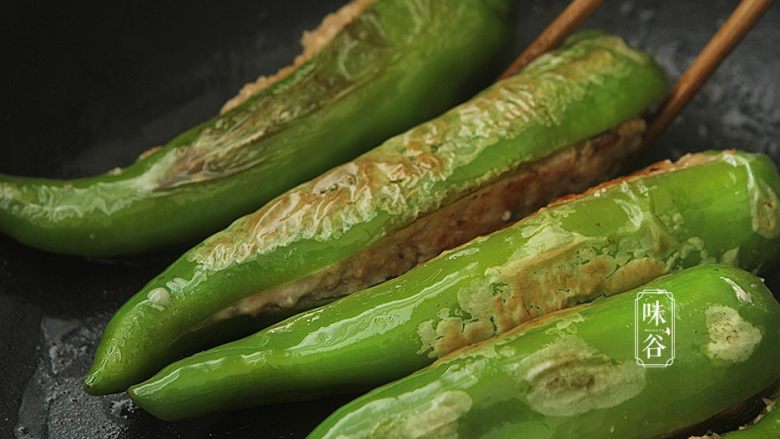 釀尖椒,煎片刻后再翻动一面,使青椒煎成虎皮状;