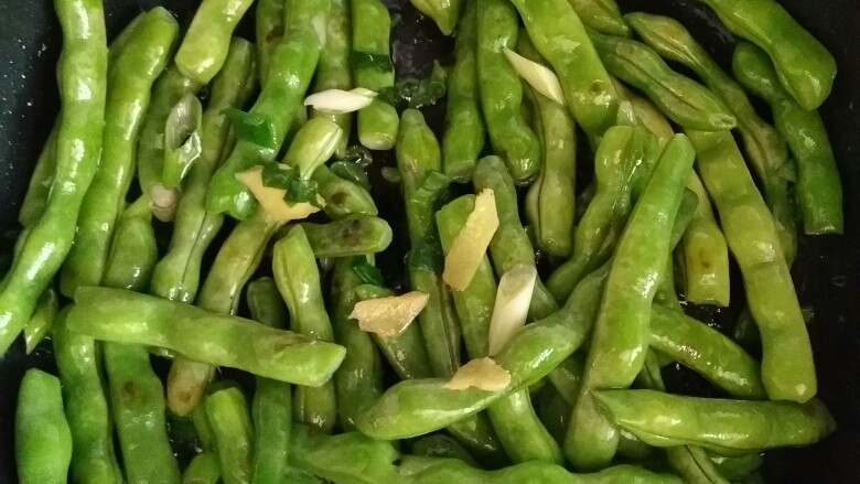家常排骨炖芸豆,当芸豆均沾油后,放入大葱和姜,炒出香味。