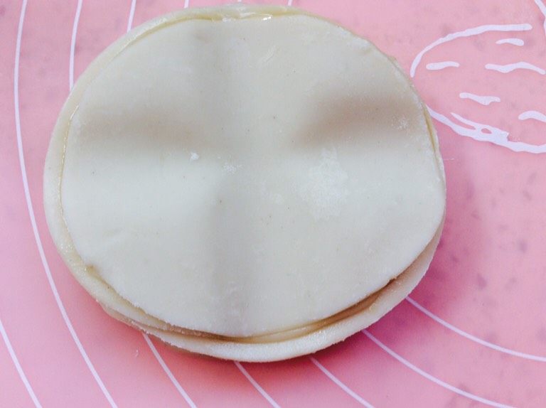 蒸多层煎饼,用擀面杖压上两道十字轻轻的从中间向外擀,两面换着擀,一面擀两下,翻过来在擀,一直擀大。