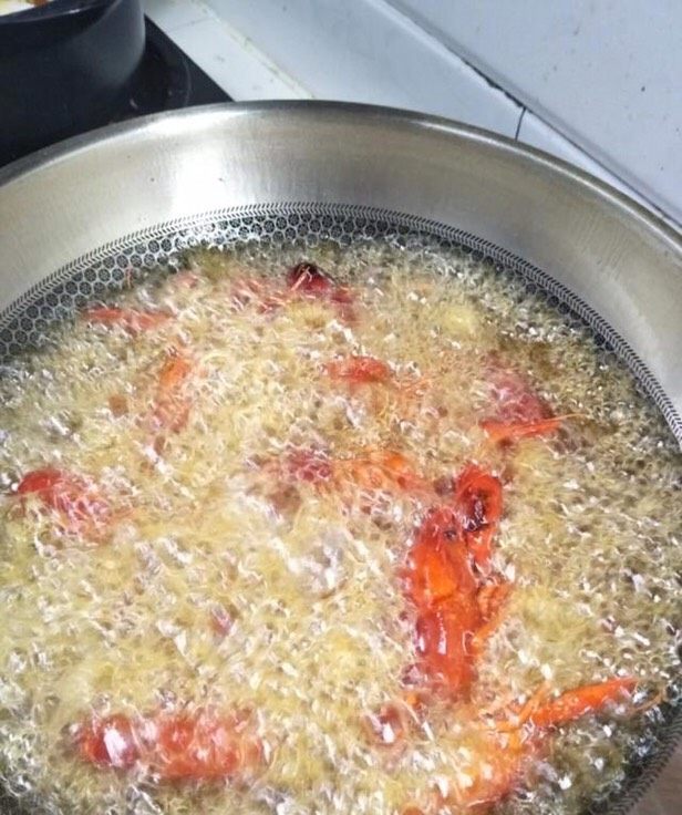 麻辣小龙虾,锅中加入油烧至六成热,把小龙虾下入锅中炸,炸至外表金黄色捞出控油