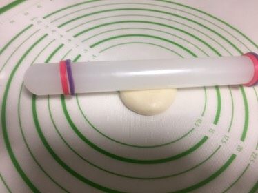 豆沙蛋黄酥,收口的地方朝上,用手压一下,擀面杖放在面团中间。
