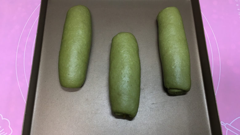 抹茶凤梨全麦面包,收口处压在下方,三个都整形好后移到烤盘中,使用烤箱发酵功能进行二次发酵,发酵同时烤箱中放一碗温水。