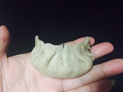 小茴香饺子,包成这样的饺子。怎么包呢,这里说一下:一个圆形的皮,放上馅,中间捏一下,可以把饺子放桌上,左手把前面的那个皮折边,先折靠近中间那个褶子,再慢慢靠边折,一共四个,右手折边,一共四个。这样就好了。还算漂亮吧。