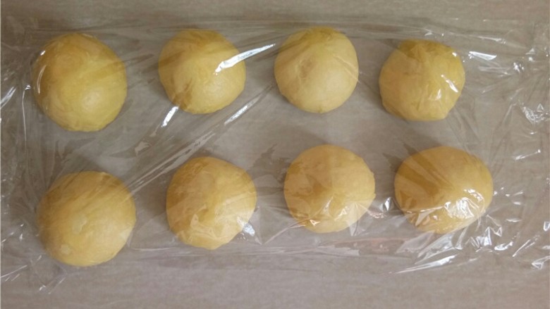 椰蓉花朵面包,醒发结束,将面团分成10个小面团滚圆盖上保鲜膜,松弛15分钟。