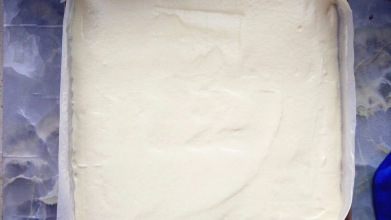 黄桃奶油蛋糕卷,倒入铺了油纸的金盘中,表面刮平