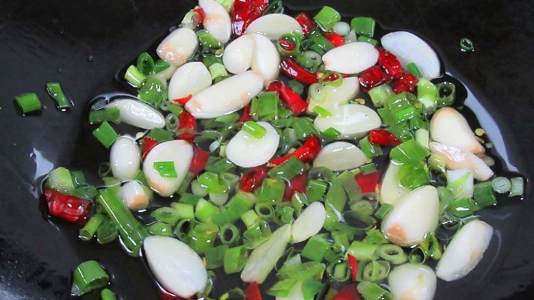 丝瓜炖豆腐,热锅注入油,烧至五分热,下入蒜瓣、姜丝、辣椒、葱等翻炒