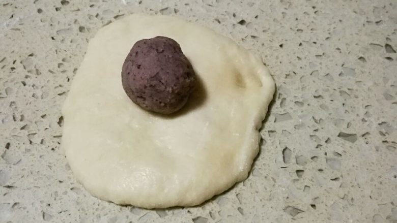 砂锅挤挤猪头包,取其中一个小面团,压扁排气,放入一个豆沙馅,包好,收口朝下。