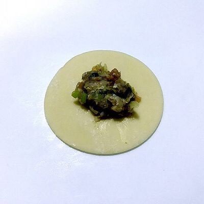 四喜饺子，让生活喜气洋洋,拿一个饺子皮，取适量肉馅放入饺子皮当中。