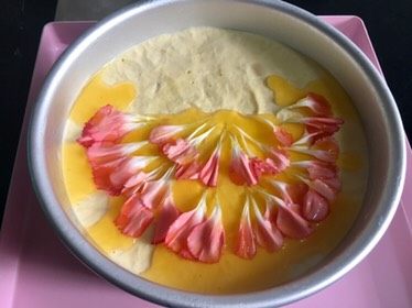 芒果慕斯鲜花蛋糕,用小勺舀出少量的镜面液体,倒在花瓣上,不要太多,容易把摆好的形状冲散,然后去冷藏二三十分钟,凝固了就行,这样就可以把花瓣固定住了。