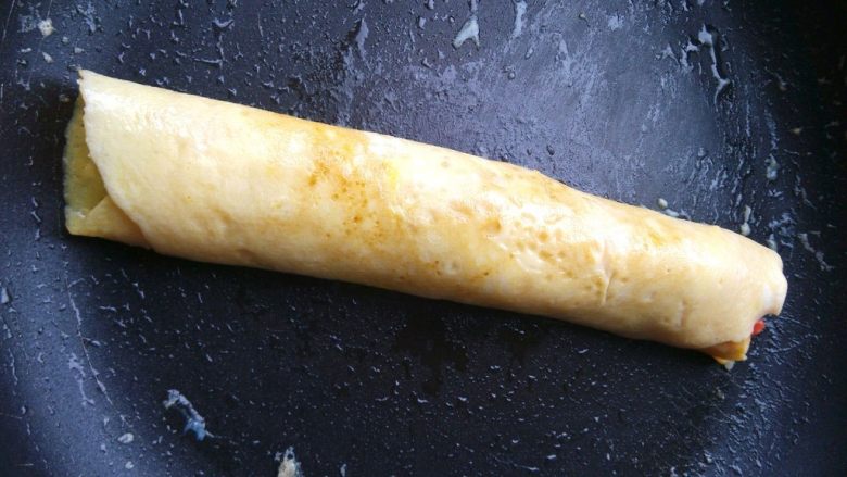 紫菜蛋包饭,继续卷动蛋饼,把整个米饭包成长条,接口在底部