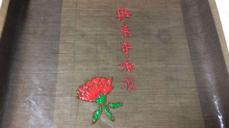 手绘母亲节蛋糕,裱花袋剪一个小口挤出图案字体，送入提前预热的烤箱180度烤三分钟，马上取出金盘放在一边。