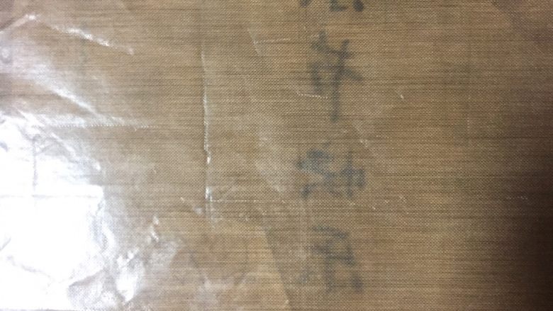 手绘母亲节蛋糕,事先写好的字正面朝下放在烤盘上,康乃馨也放在一起,然后盖上油布。