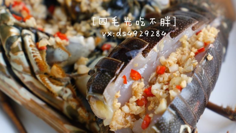 蒜蓉蒸龙虾,将翻炒过的蒜蓉和辣椒,均匀地洒在洗净开背处理过的龙虾上。