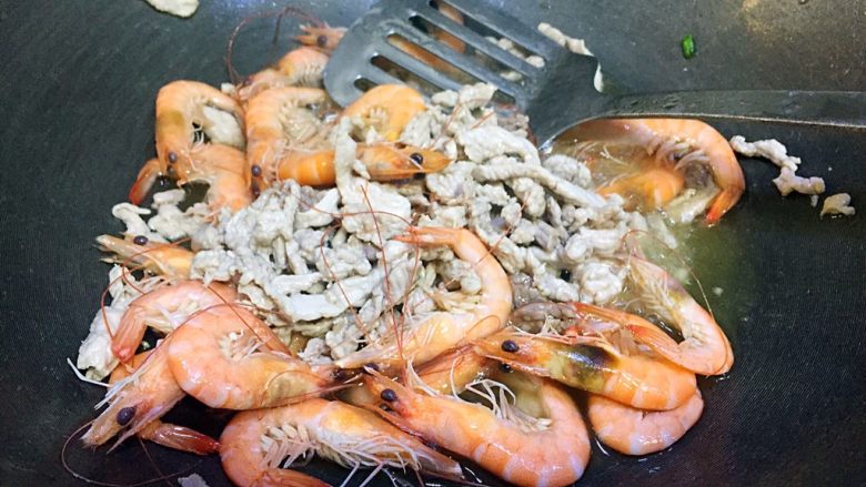 肉丝鲜虾炒面,锅里倒入适量的油,五六成热,先倒入肉丝过个油,然后倒入煮好的虾一起翻炒;