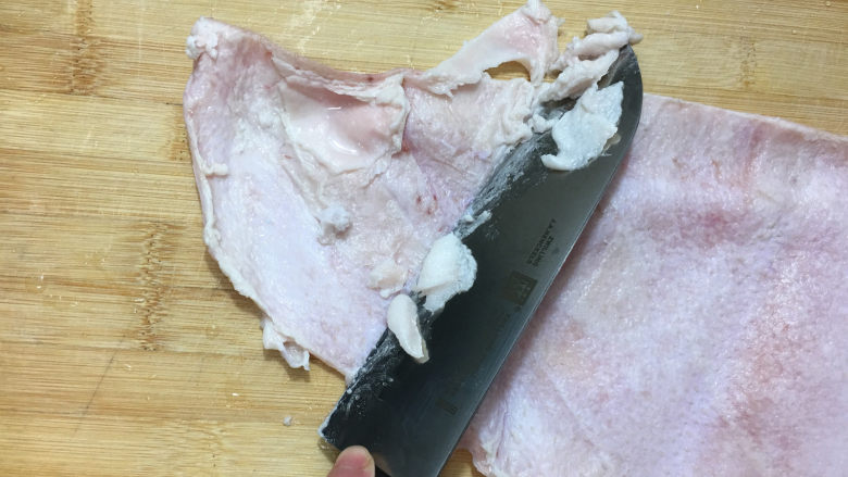 自制肉皮冻,将买回来肉皮洗净,用刀将肉皮里残留的肥肉清理干净。
