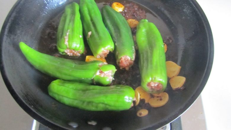 青椒酿肉,煸炒出香味后将酿好的青椒放入里面先干煸一下;