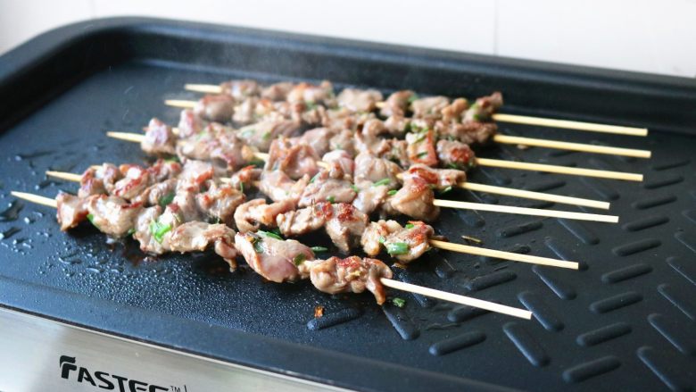 烤羊肉串,翻面再煎一会,变色后继续翻面。
