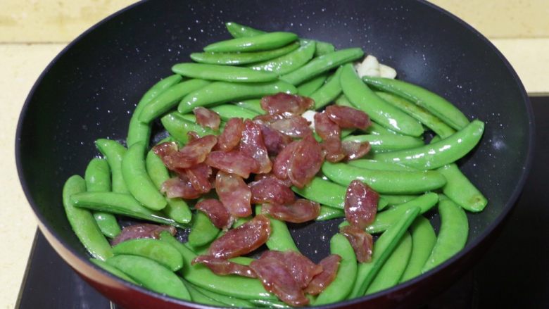 甜豆炒腊肠,倒入腊肠,继续翻炒两三分钟至熟
