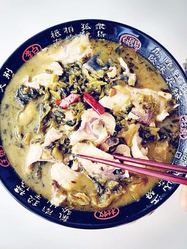 家常酸菜鱼,盛出后,将鱼片在碗中堆起,稍高于汤面,少许蒜粒洒在鱼片上