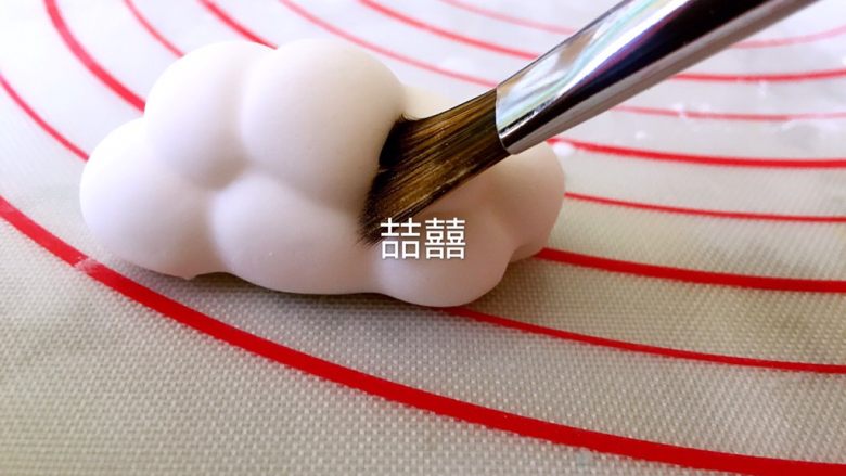 翻糖立体云朵,用软毛刷轻压糖皮,使之与翻糖球贴合,让球与球连接的缝隙更清晰