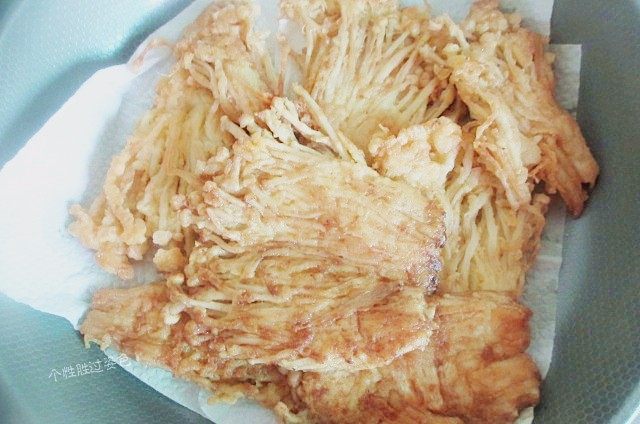 孜然黄金金针菇,把炸好的金针菇放在吸油纸上,吸掉多余油