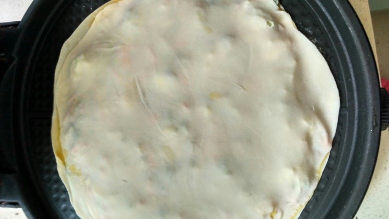 单饼版鸡蛋饼-菜煎饼,取另外一个饼盖上,压好一圈,防止蛋液流淌出来
盖上电饼铛,调最大火开始煎
