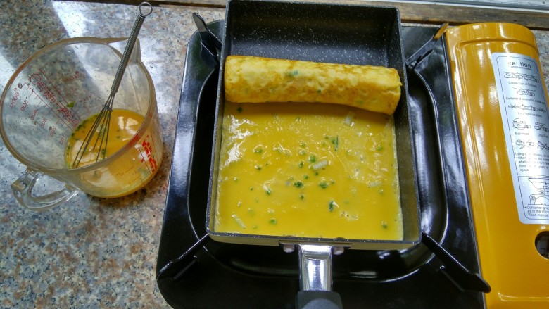 香葱玉子烧,再次倒入蛋液,再卷制,重复上面的步骤直至用完全部蛋液