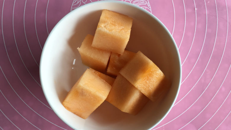 面包机版哈蜜瓜糯米糍,年糕降温的时间我们准备哈蜜瓜,把哈蜜瓜切成3厘米的小方块。
