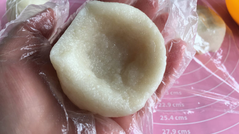 面包机版哈蜜瓜糯米糍,取出一份用手按成一个小碗形状,这样比较好放哈蜜瓜。