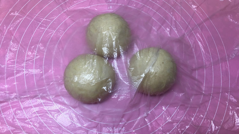 燕麦辫子花环汉堡面包,将面团取出进行排气,然后平均分成三份,滚圆后盖保鲜膜醒发15分钟。