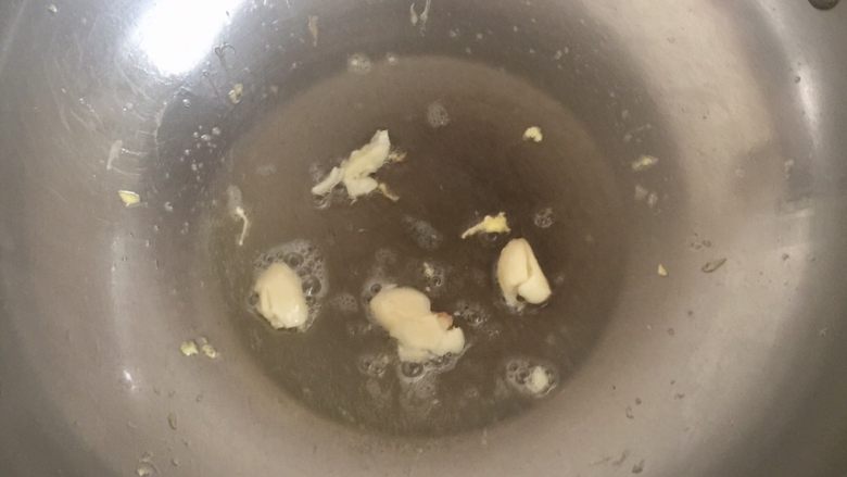 不苦的苦瓜炒蛋,油锅加热下蒜瓣,煎至闻到蒜香,转中火