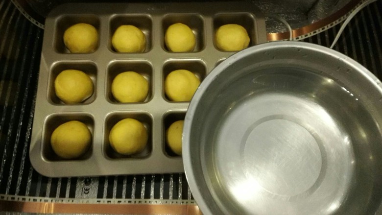 胡萝卜椰蓉菠萝巧克力豆小餐包,烤箱或者发酵箱里面放一碗热水,将模具放入,二发温度保持在38度左右,发酵到两倍大。