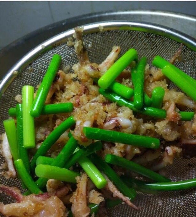 香酥鱿鱼,锅中下入油烧至五成热,把裹好淀粉的鱿鱼放到锅中炸,炸上两分钟左右,再下入蒜苔炸一分钟,一起捞出控油