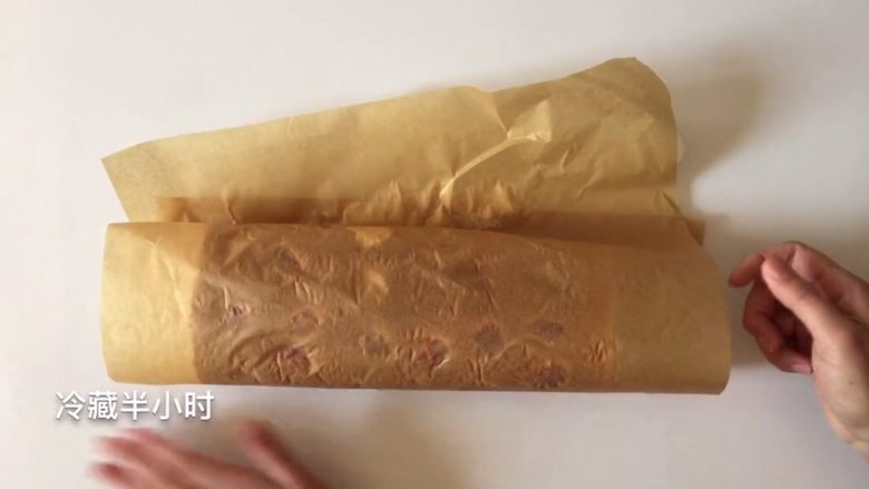 草莓三重奏蛋糕卷,卷起来后用油纸包上,放入冰箱冷藏半小时以上定型