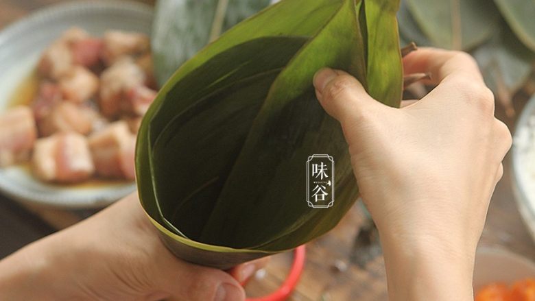 粤式海鲜咸肉粽,取2片粽叶错开一点相叠,折成一个漏斗形;